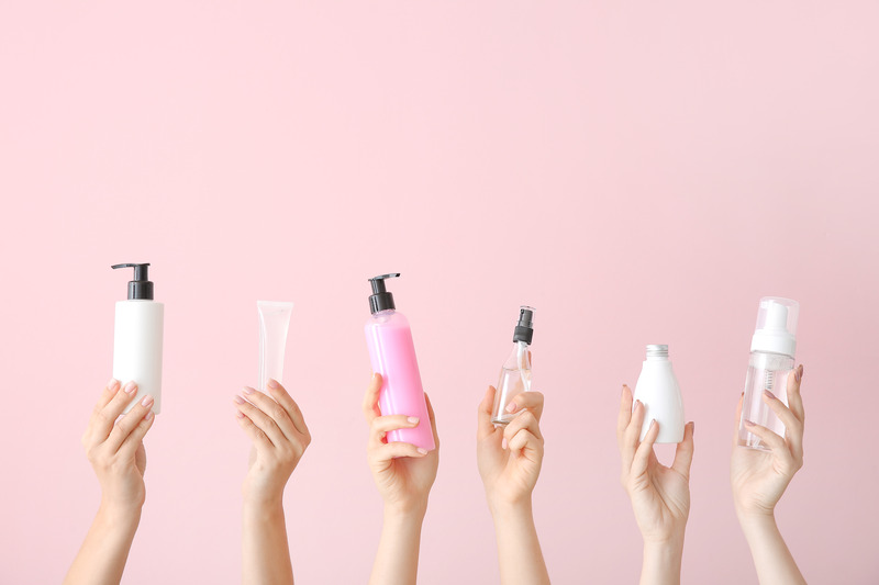 eyelash extension products - 6 hands holding a beauty bottle on pink background